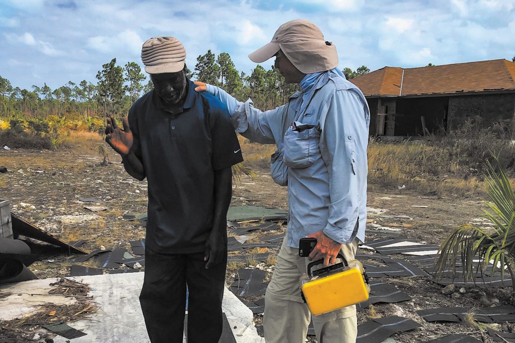 Stockton prays over a resident in a hurricane debris field