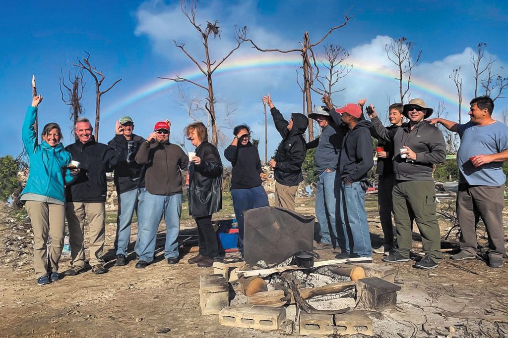people at hurricane debris field with rainbow in background