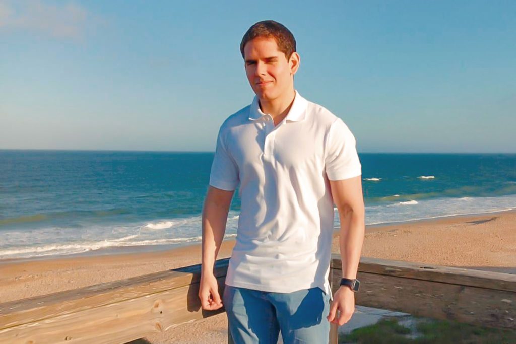Ariel Alberto Montero Valera in a polo and jeans, with a beach view in the background