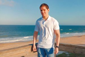 Ariel Alberto Montero Valera in a polo and jeans, with a beach view in the background