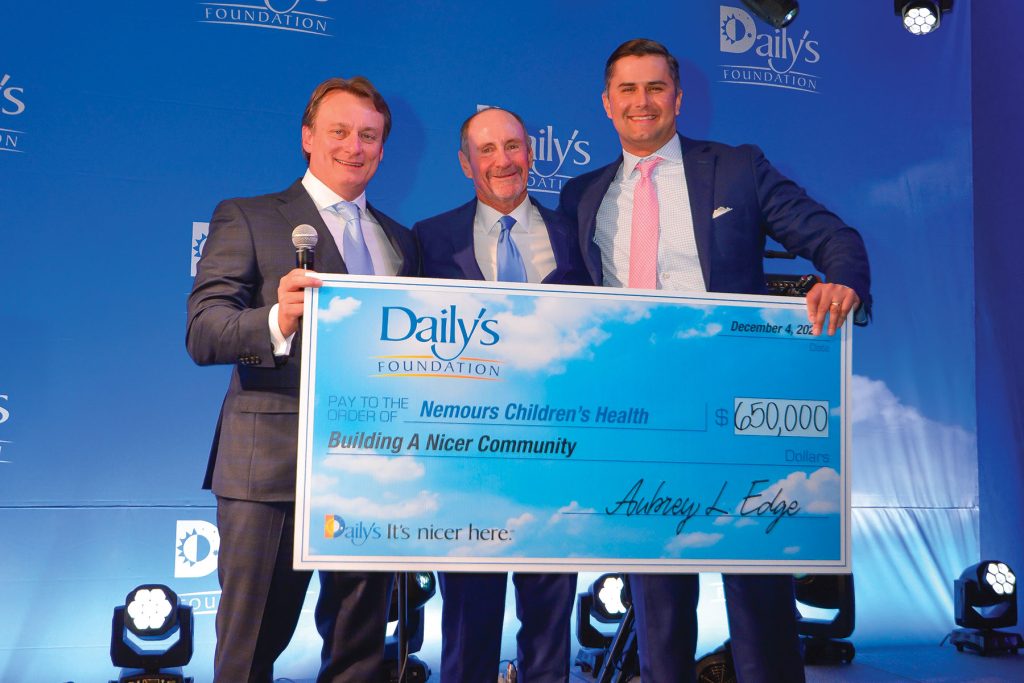 The Daily’s Foundation 3 men holding large Daily's check