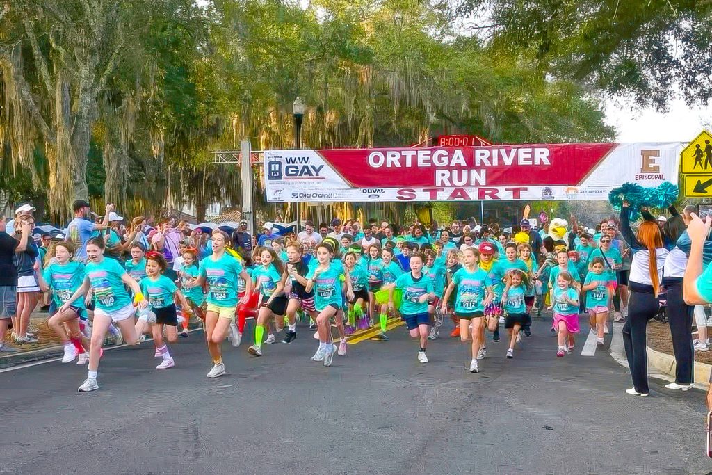 kids running with Ortega River Run banner behind them