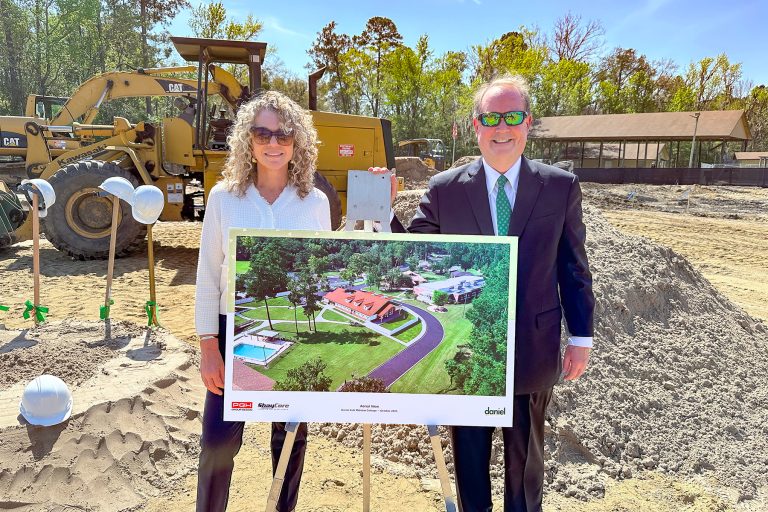 Daniel CEO Lesley Wells and Chairman of the Board of Trustees Judge Timothy Corrigan pose beside a rendering of the new cottage at the March 11 groundbreaking ceremony.