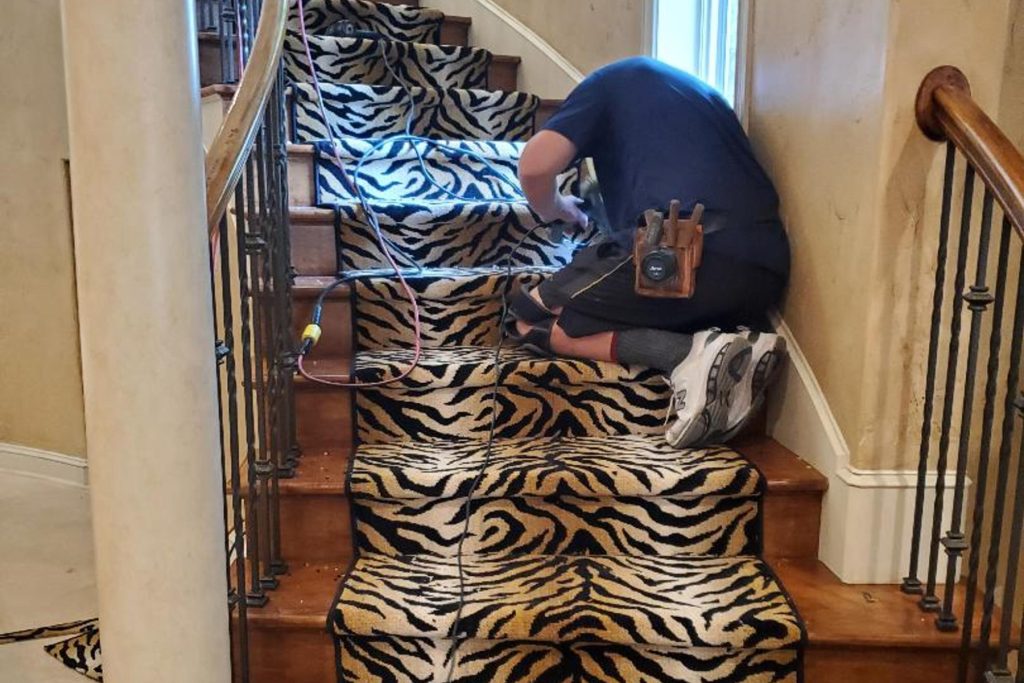 Mark Stone installing tiger pattern accent down staircase center.