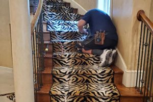 Mark Stone installing tiger pattern accent down staircase center.